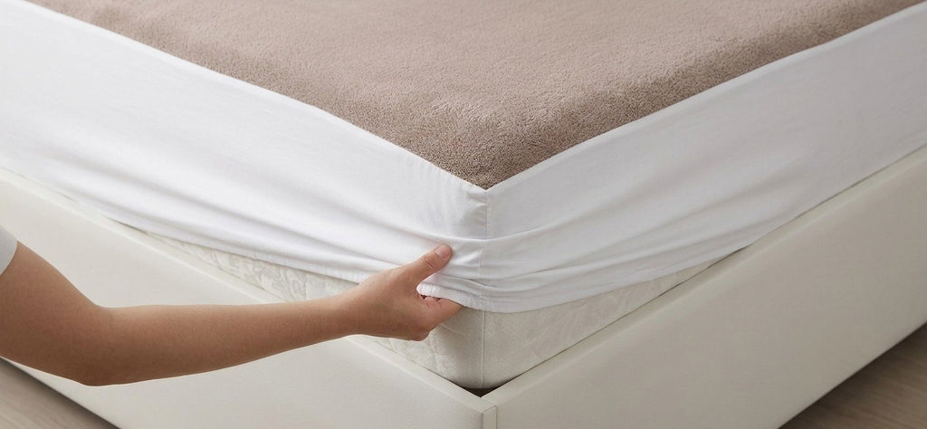 Coffee waterproof plush mattress protector fitted over a bed with an elasticated edge